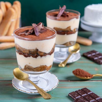 Tiramisù con ricotta in coppa, con strati di savoiardi, crema e cacao in polvere guarnito con riccioli di cioccolato