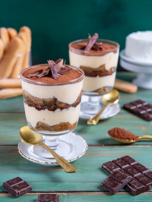 Tiramisù con ricotta in coppa, con strati di savoiardi, crema e cacao in polvere guarnito con riccioli di cioccolato