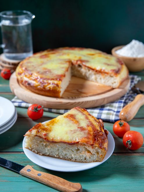 Pizza liquida con mozzarella filante e salsa di pomodoro, una fetta in primo piano che mostra l'impasto soffice e alveolato