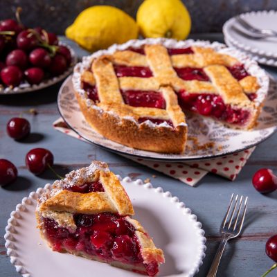 Cherry pie con ripieno di ciliegie e griglia di pasta frolla, una fetta servita in primo piano