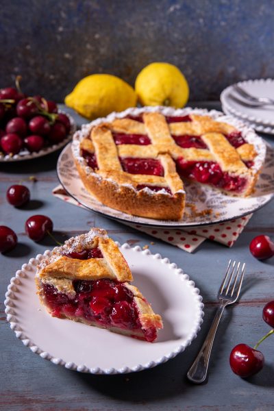 Cherry pie con ripieno di ciliegie e griglia di pasta frolla, una fetta servita in primo piano