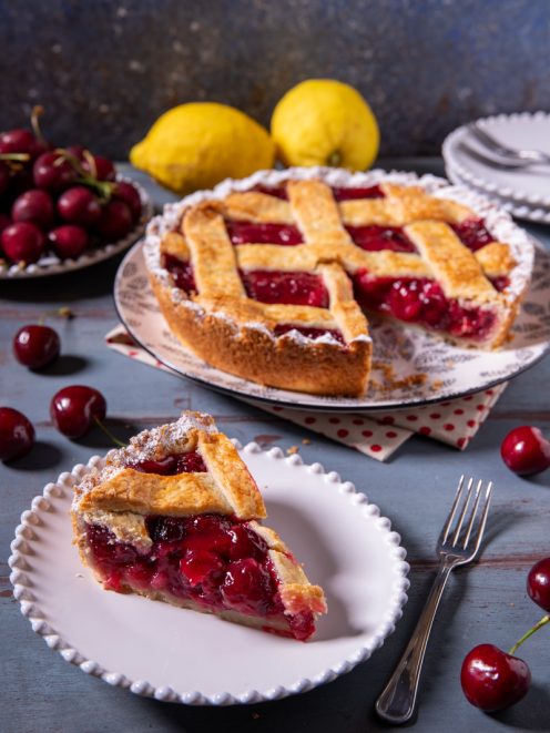 Cherry pie con ripieno di ciliegie e griglia di pasta frolla, una fetta servita in primo piano
