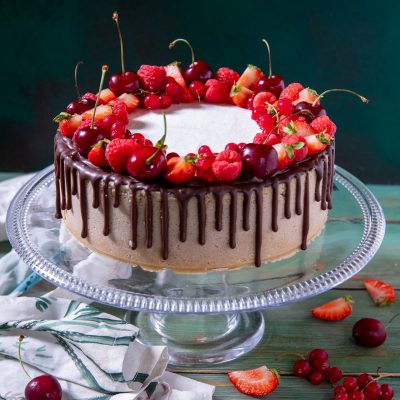 Drip cheesecake ai frutti rossi e ciliegie con colata di cioccolato e corona di fragole, lamponi e ciliegie fresche