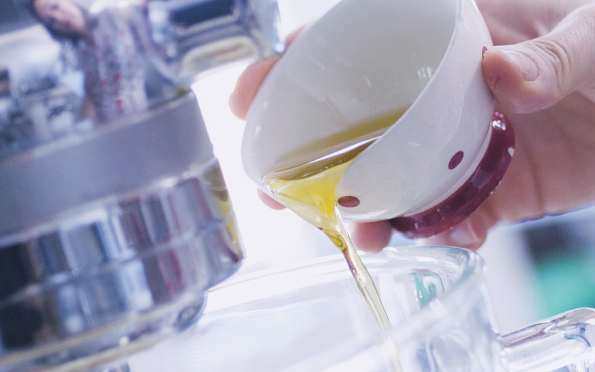 Olio versato a filo in una caraffa di vetro durante la preparazione dell'impasto