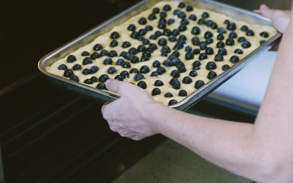 Teglia con impasto lievitato coperto di chicchi d'uva fragola pronta per entrare in forno