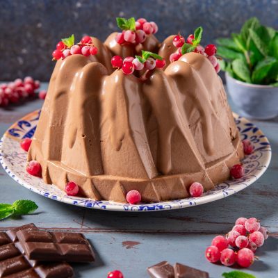 Bavarese al cioccolato a forma di ciambella guarnita con ribes rosso e foglie di menta