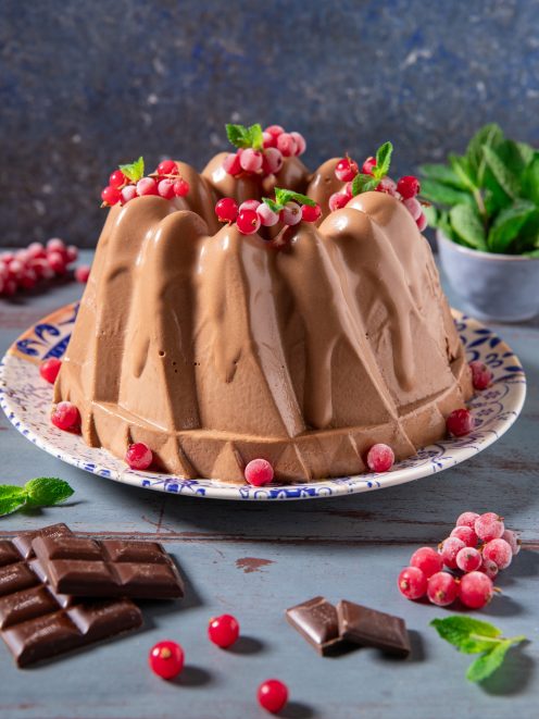 Bavarese al cioccolato a forma di ciambella guarnita con ribes rosso e foglie di menta
