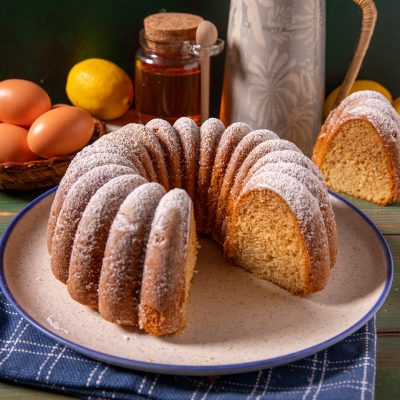 Ciambella al miele spolverata di zucchero a velo, con una fetta tagliata che mostra la mollica soffice