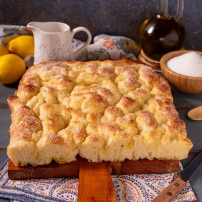 Focaccia dolce ligure appena sfornata, con superficie dorata e lucida cosparsa di zucchero