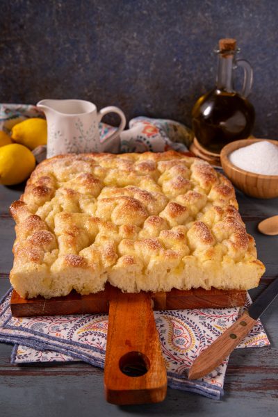 Focaccia dolce ligure appena sfornata, con superficie dorata e lucida cosparsa di zucchero