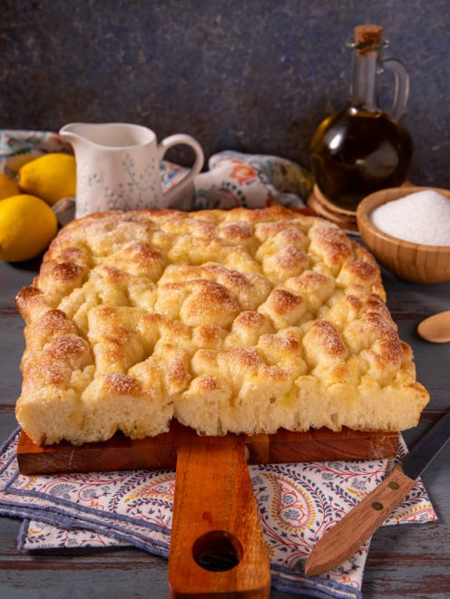 Focaccia dolce ligure appena sfornata, con superficie dorata e lucida cosparsa di zucchero
