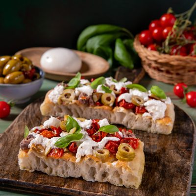 Focaccia millebolle con pomodorini secchi, olive verdi, stracciatella e basilico fresco