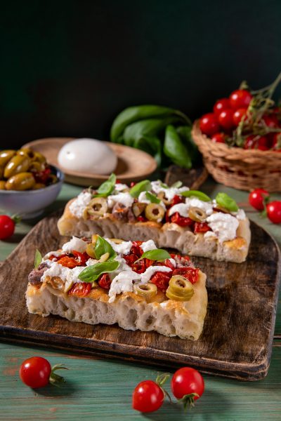 Focaccia millebolle con pomodorini secchi, olive verdi, stracciatella e basilico fresco