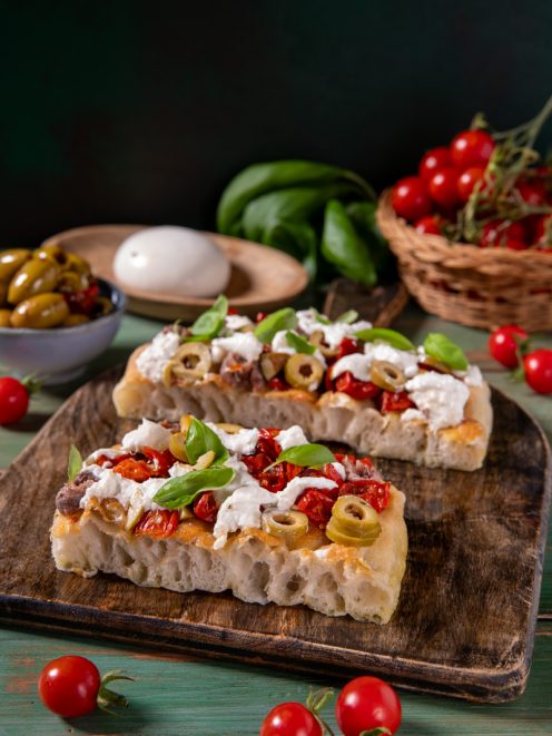 Focaccia millebolle con pomodorini secchi, olive verdi, stracciatella e basilico fresco