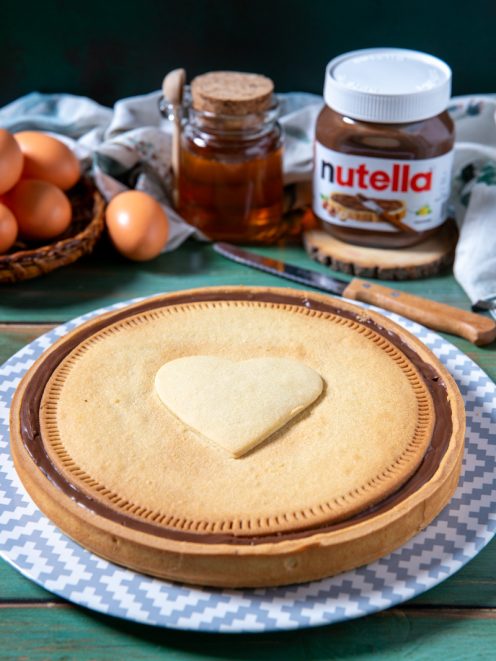 Nutella Biscuits Cake con copertura di crema al cioccolato e biscotto a cuore al centro