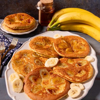 Pancake alla banana caramellata serviti a torretta e disposti a raggiera con fettine fresche