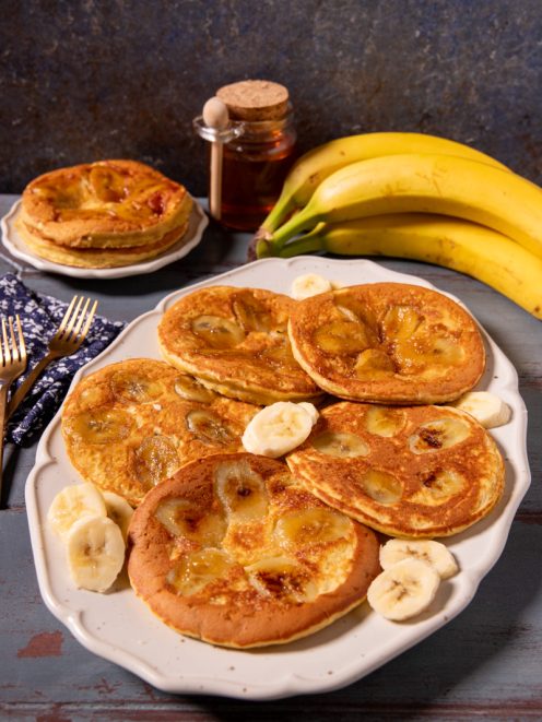 Pancake alla banana caramellata serviti a torretta e disposti a raggiera con fettine fresche