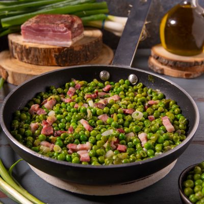 Piselli in padella con pancetta a cubetti e cipollotti saltati insieme