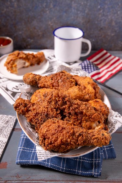 Pollo fritto in stile KFC con crosta dorata e croccante, servito con pezzi sovrapposti