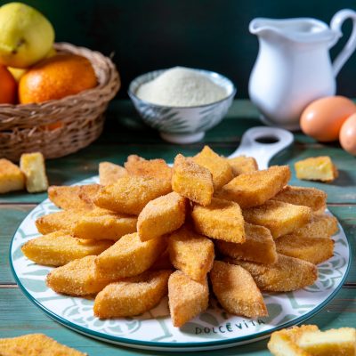 Semolino dolce fritto in pezzi romboidali impanati, disposti a ventaglio su un piatto da portata
