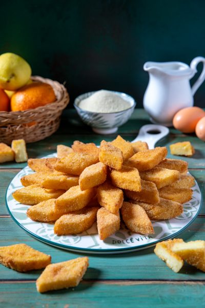 Semolino dolce fritto in pezzi romboidali impanati, disposti a ventaglio su un piatto da portata