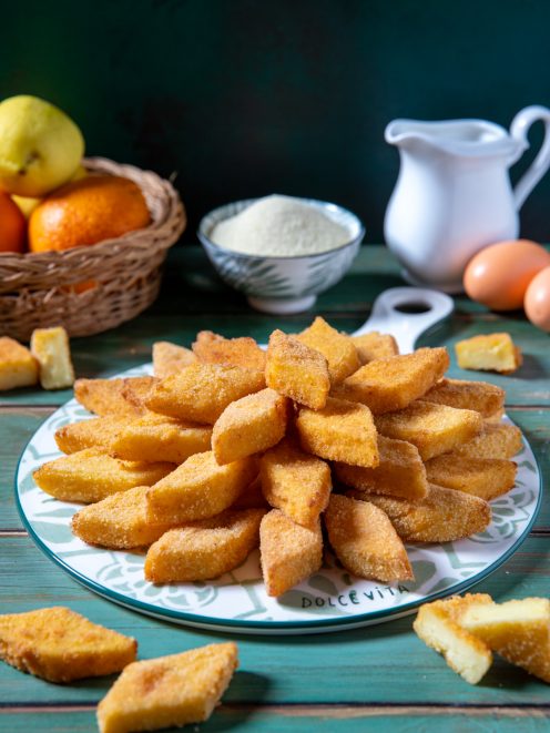 Semolino dolce fritto in pezzi romboidali impanati, disposti a ventaglio su un piatto da portata