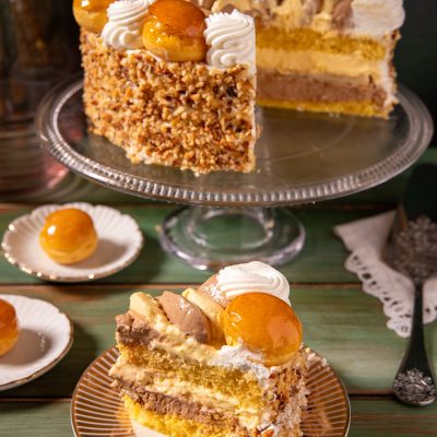 Torta Saint Honoré a strati con crema, bignè caramellati, granella di nocciole e ciuffi di panna