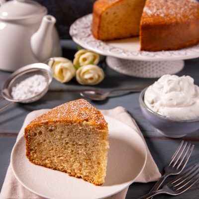 Torta alla panna con una fetta tagliata che mostra l'interno soffice, spolverata di zucchero a velo