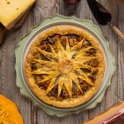 Torta salata girasole con decoro a petali di pasta sfoglia, semi di sesamo e ripieno di zucca e patate