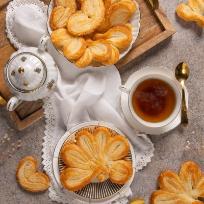 Ventagli e cuoricini di pasta sfoglia dorata e croccante serviti con tè caldo
