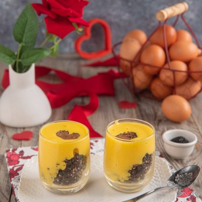 Bicchierini di zabaione con crumble al tartufo, strati di crema gialla su briciole scure e scaglia di tartufo in superficie