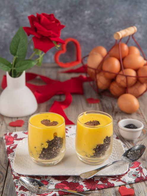 Bicchierini di zabaione con crumble al tartufo, strati di crema gialla su briciole scure e scaglia di tartufo in superficie