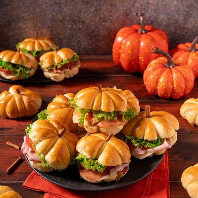 Panini zucca dalla forma di piccole zucche, farciti con insalata verde, prosciutto e formaggio, con un pezzetto di cannella come picciolo
