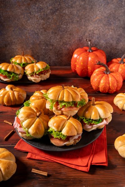 Panini zucca dalla forma di piccole zucche, farciti con insalata verde, prosciutto e formaggio, con un pezzetto di cannella come picciolo