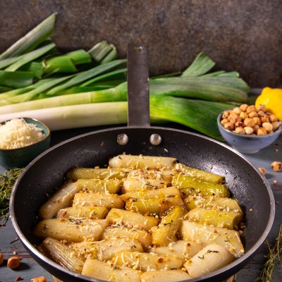 Porri in padella con Parmigiano e nocciole: tronchetti di porro dorati con formaggio grattugiato, nocciole tritate e timo