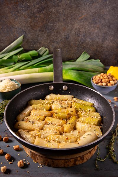 Porri in padella con Parmigiano e nocciole: tronchetti di porro dorati con formaggio grattugiato, nocciole tritate e timo
