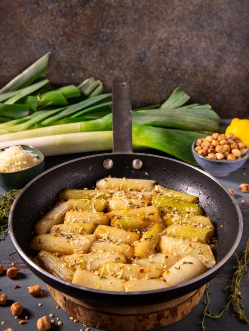 Porri in padella con Parmigiano e nocciole: tronchetti di porro dorati con formaggio grattugiato, nocciole tritate e timo