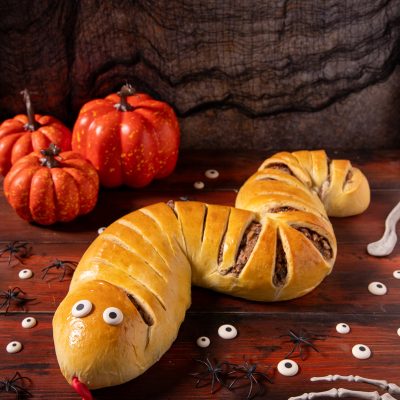 Serpente strudel di pasta lievitata dorata con occhi e lingua rossa, tagli sul dorso che lasciano vedere il ripieno di carne