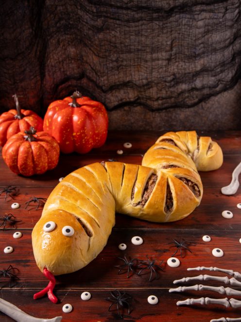 Serpente strudel di pasta lievitata dorata con occhi e lingua rossa, tagli sul dorso che lasciano vedere il ripieno di carne